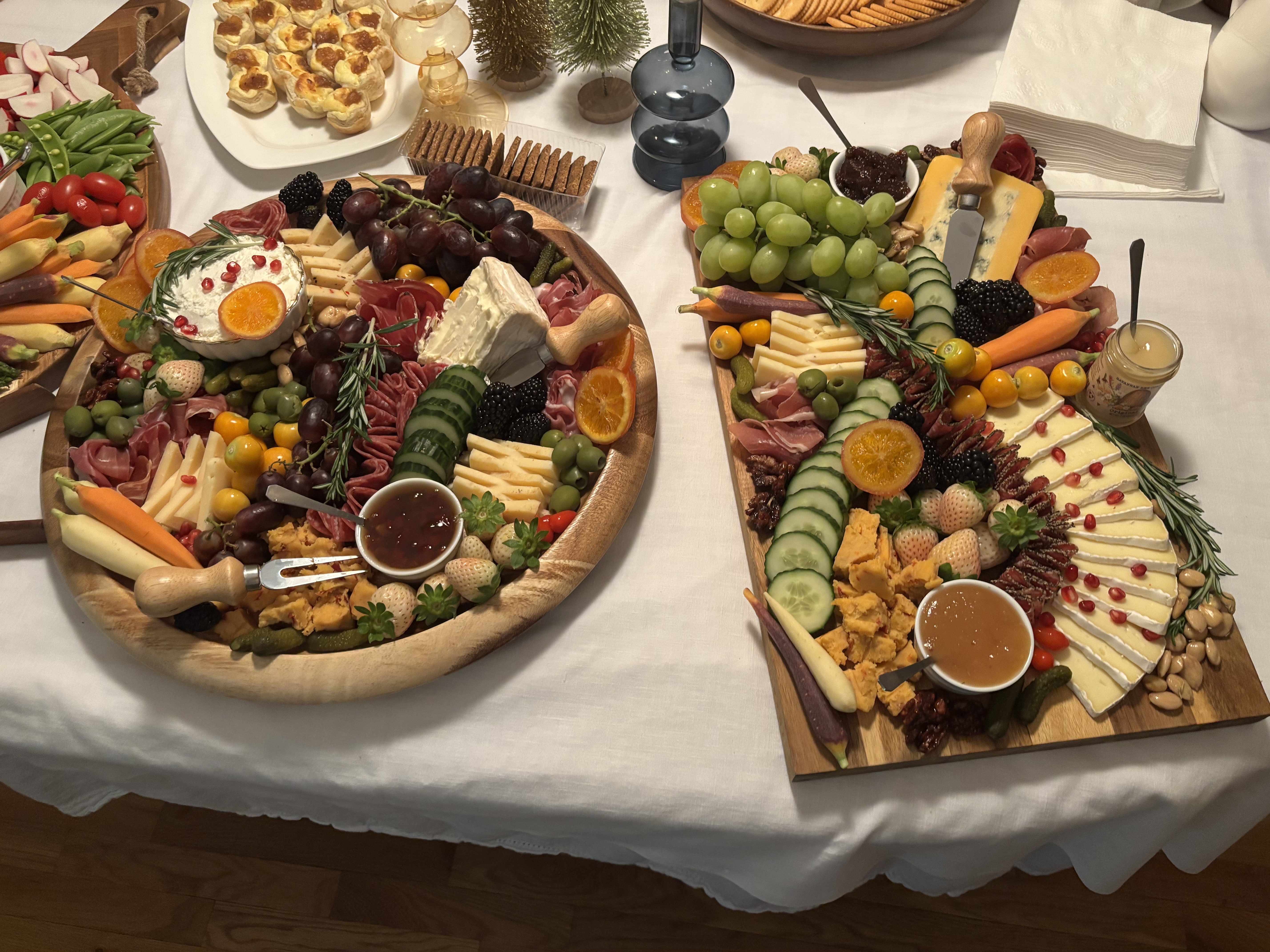 Two charcuterie boards, one on a round platter and one on a rectangular platter.