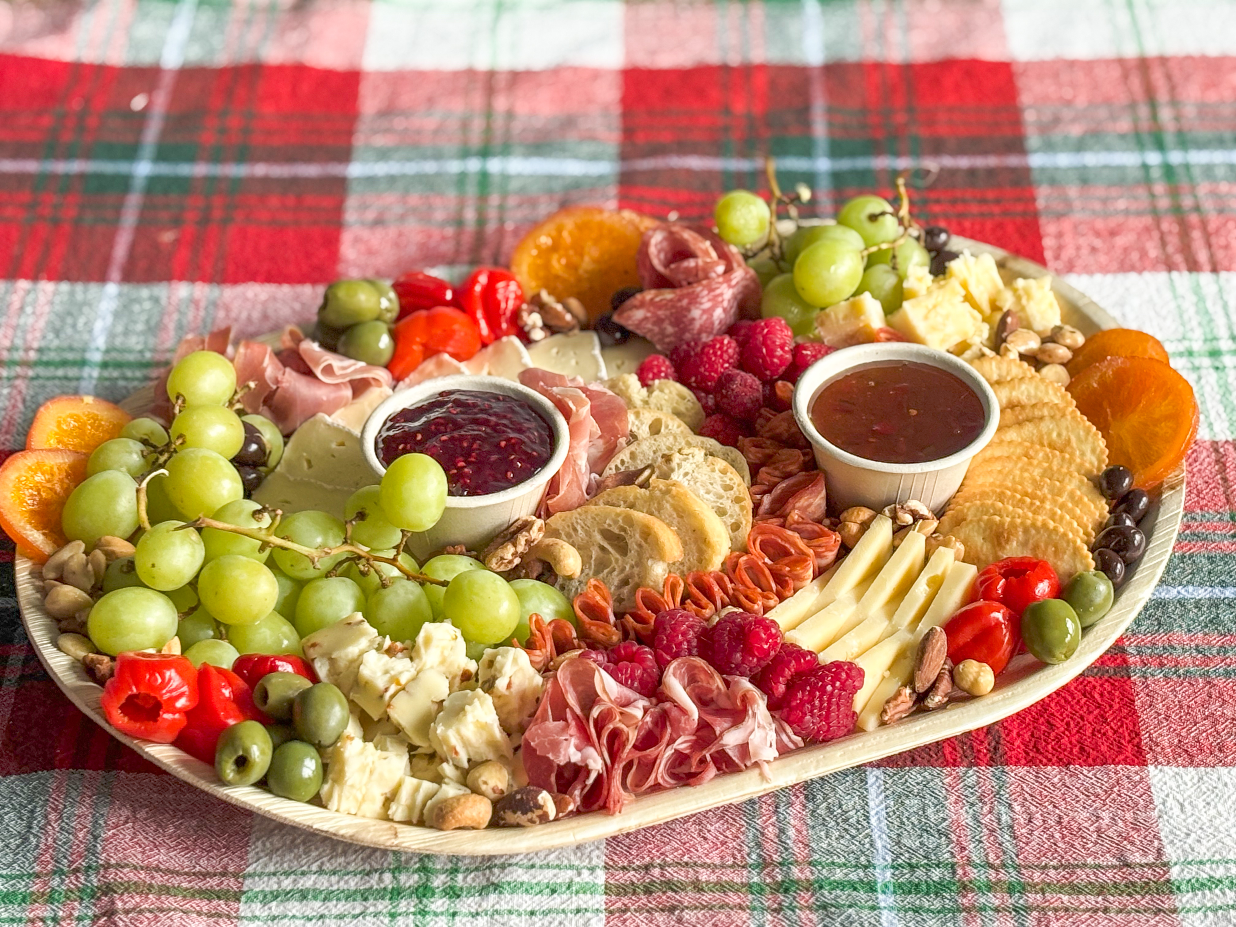 A bright and colorful charcuterie board on a Christmas themed tablecloth.