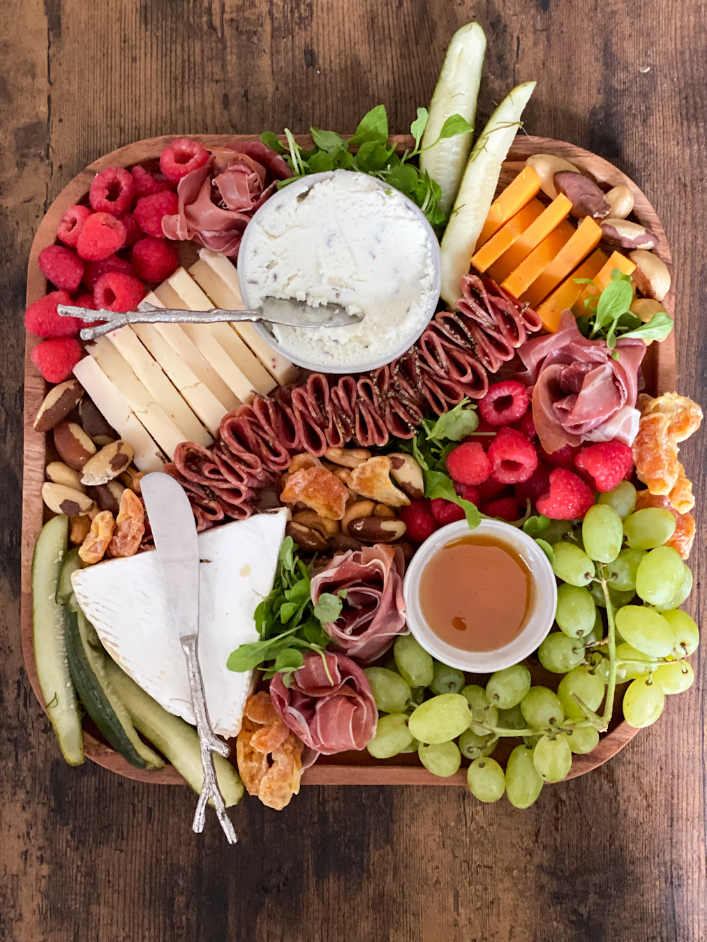 A small charcuterie board with bright reds and greens.