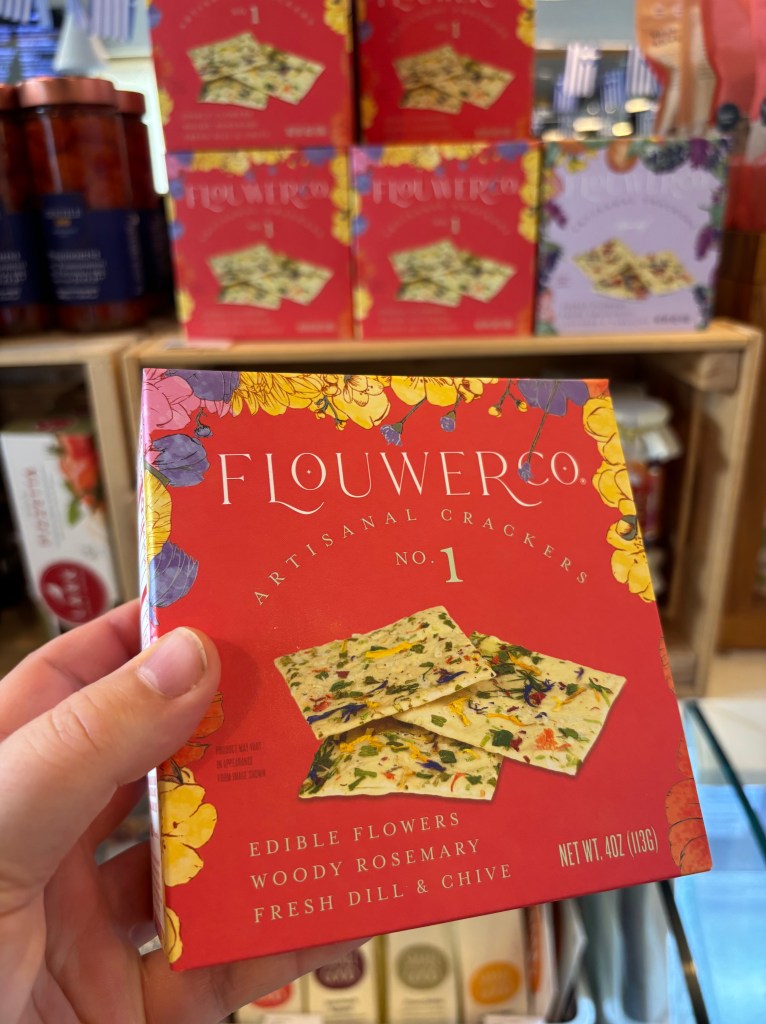A box of crackers for charcuterie with edible flowers pressed into them.